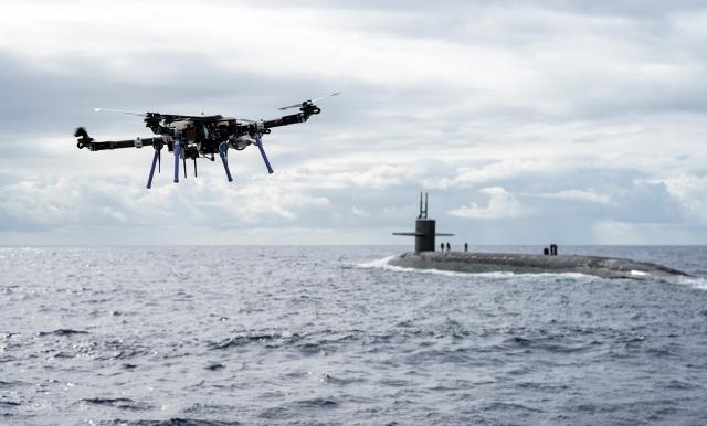 An unmanned aerial vehicle approaches the USS Henry M. Jackson (SSBN-730) with a payload during a replenishment evaluation. The role of unmanned systems in the Navy must flow from larger questions about strategy and purpose.